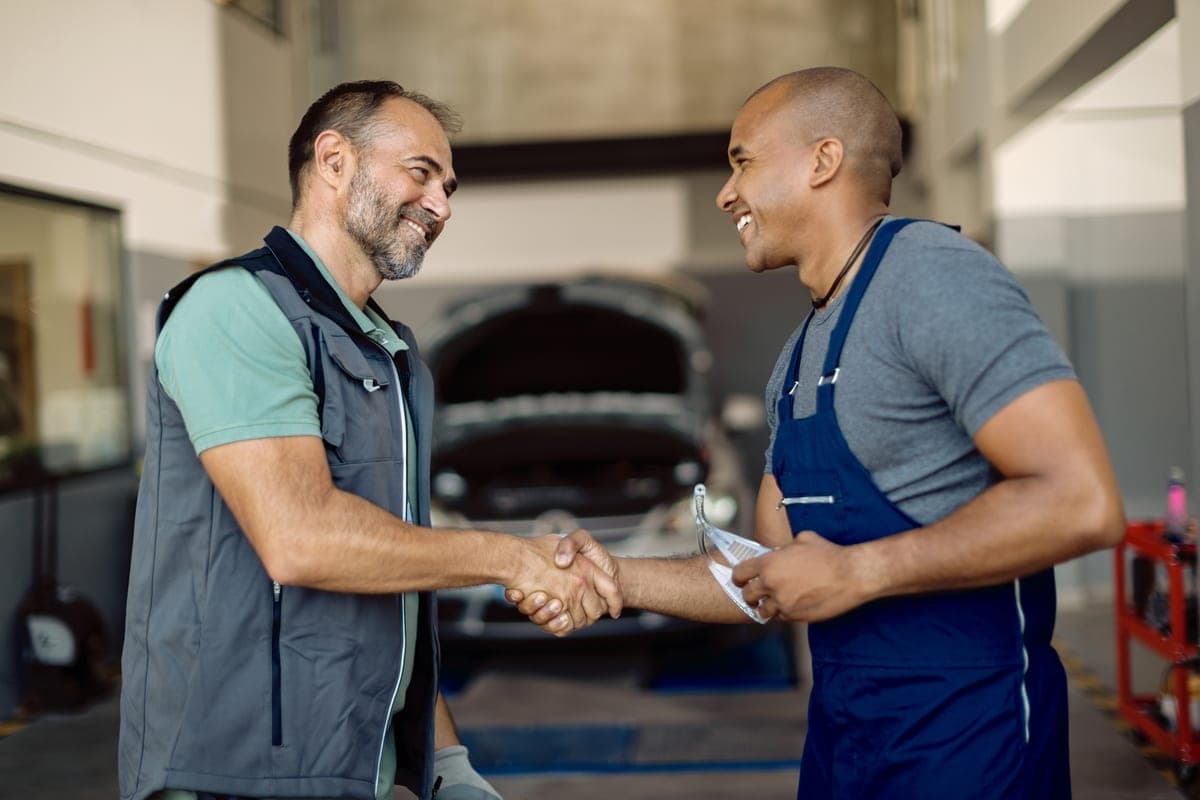 Two mechanics greeting each other in an auto repair shop